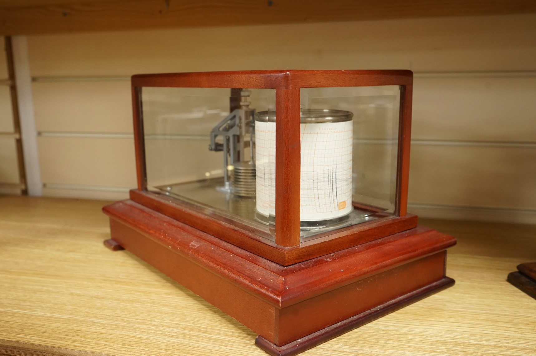 A 1970s Casella mahogany cased barograph with bevelled glass panels and a drawer underneath containing a good quantity of paper slips and instruction leaflet.